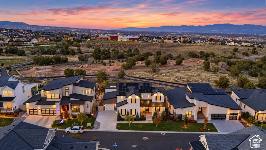 Aerial view of contemporary multi-story residences featuring peaked rooflines, solar panel arrays, multi-car garages, and mountain backdrops