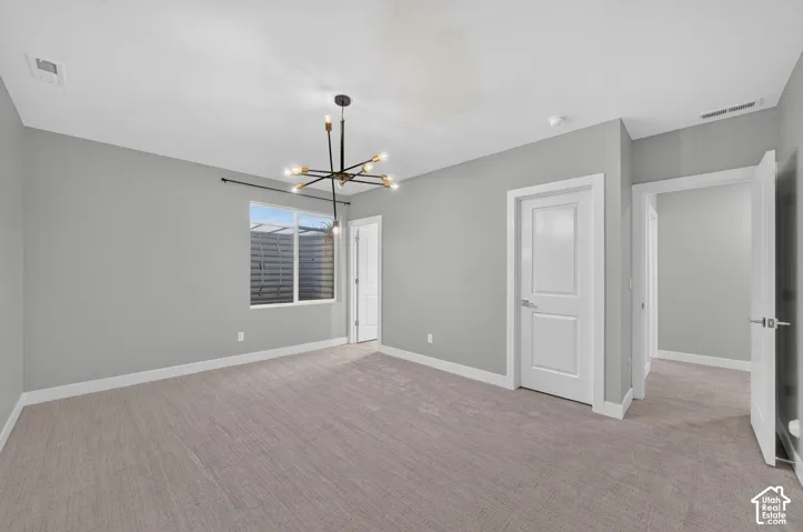 Neutral-toned wall paint, neutral carpeting, multi-arm sputnik-style chandelier, single-hung window with a metal curtain rod, and three-panel interior doors