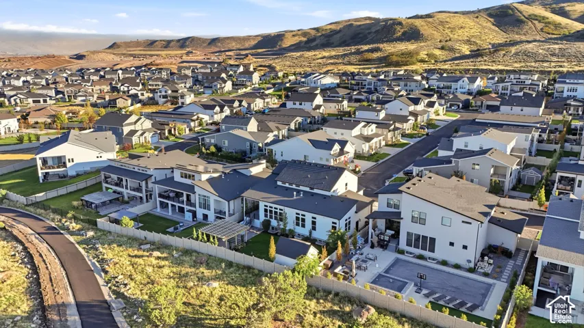 Aerial perspective of residential lots featuring fenced rear yards, paved walkways, hardscaped patios, and mountainous topography