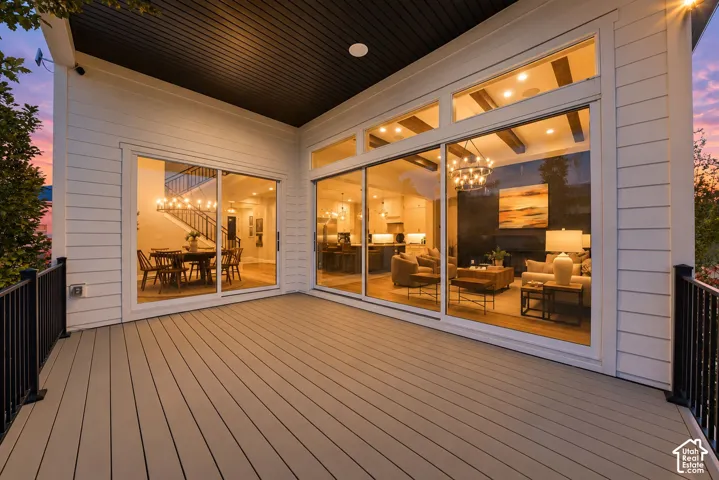 Covered deck featuring composite decking, black metal railings, and expansive glass sliding doors