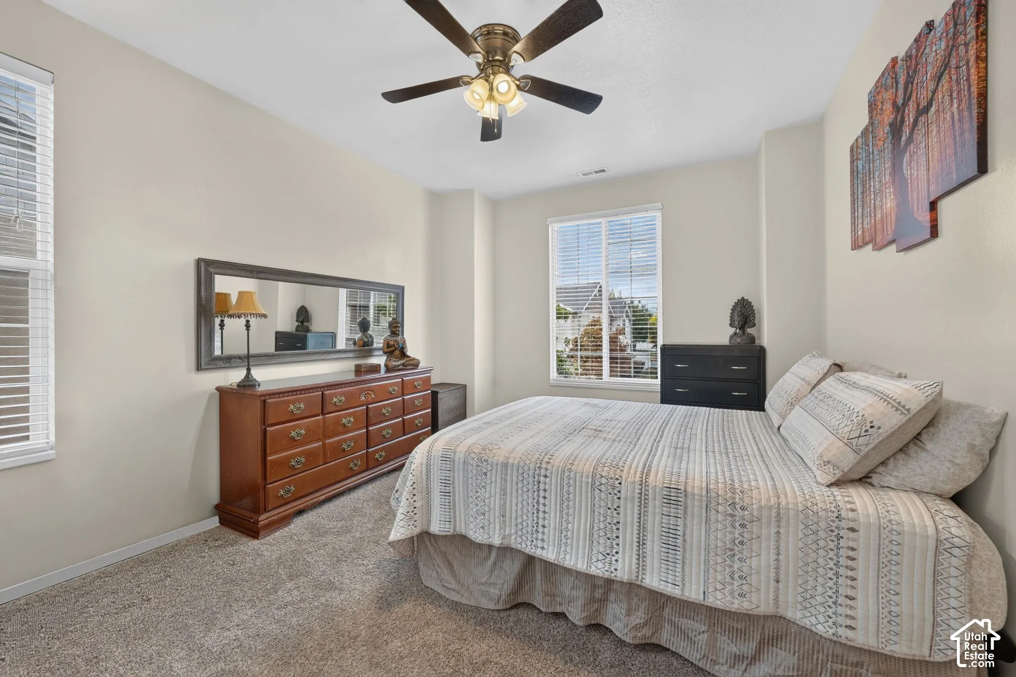 Primary bedroom with two windows and ceiling fan.