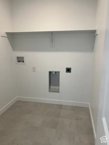 Dedicated utility area featuring tile flooring, neutral walls, and an overhead shelf