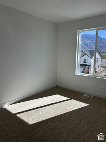 Neutral interior featuring carpeting and a large window with mountain scenery