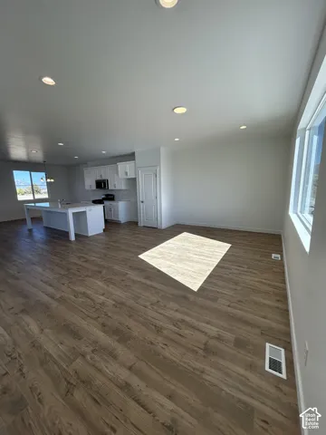 Open floor plan featuring wood-finish flooring, recessed lighting, expansive windows, white cabinetry, and a central kitchen island