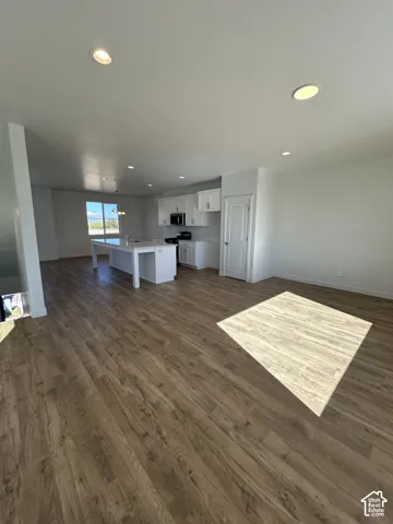 Open-concept kitchen featuring white cabinetry, a central island, recessed lighting, and wood-finish flooring