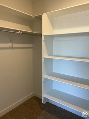 Walk-in closet featuring white built-in shelving and dual-tier metal hanging rods