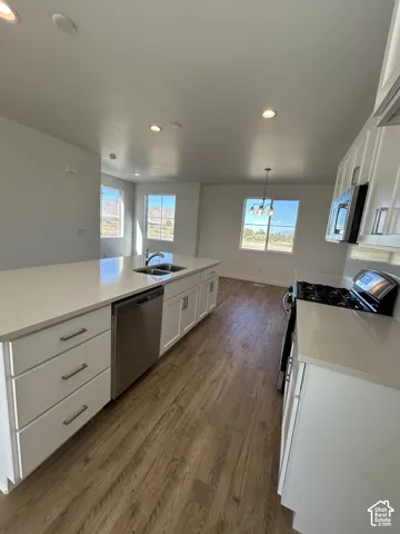 Kitchen featuring white cabinetry, solid-surface countertops, stainless steel appliances, recessed lighting, and wood-finish flooring