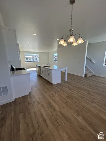 Kitchen featuring a center island, white cabinetry, light-toned stone countertops, integrated recessed lighting, and wood-finish flooring