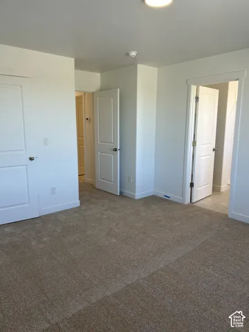 Neutral-toned carpeting, crisp white walls, flush-mount ceiling lighting, and solid-core interior doors with satin nickel hardware