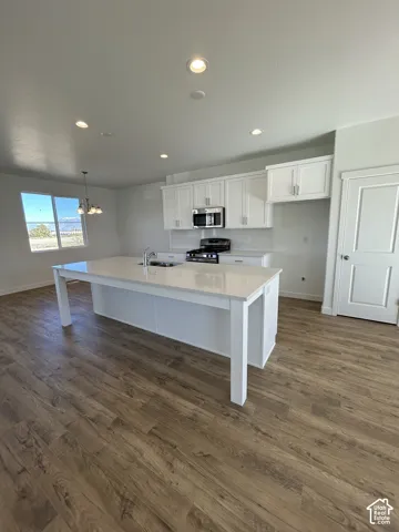 Kitchen featuring white cabinetry, an expansive center island with a light-toned countertop, wood-finish flooring, and recessed ceiling lighting
