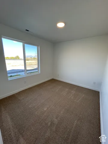 Neutral-toned interior featuring wall-to-wall carpeting, crisp white walls, and a large window with mountain scenery