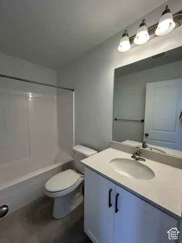 Bathroom featuring a vanity with a white cabinet, stone-finish countertop, oval undermount sink, three-light fixture, and a tub-shower combination with a surround