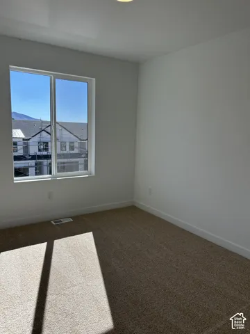 Neutral-toned wall-to-wall carpeting, crisp white walls, and a large sliding window with mountain scenery