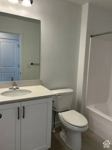 Bathroom featuring a white vanity cabinet with stone-composite countertop, undermount sink, chrome faucet, wall-to-wall mirror, and acrylic tub surround