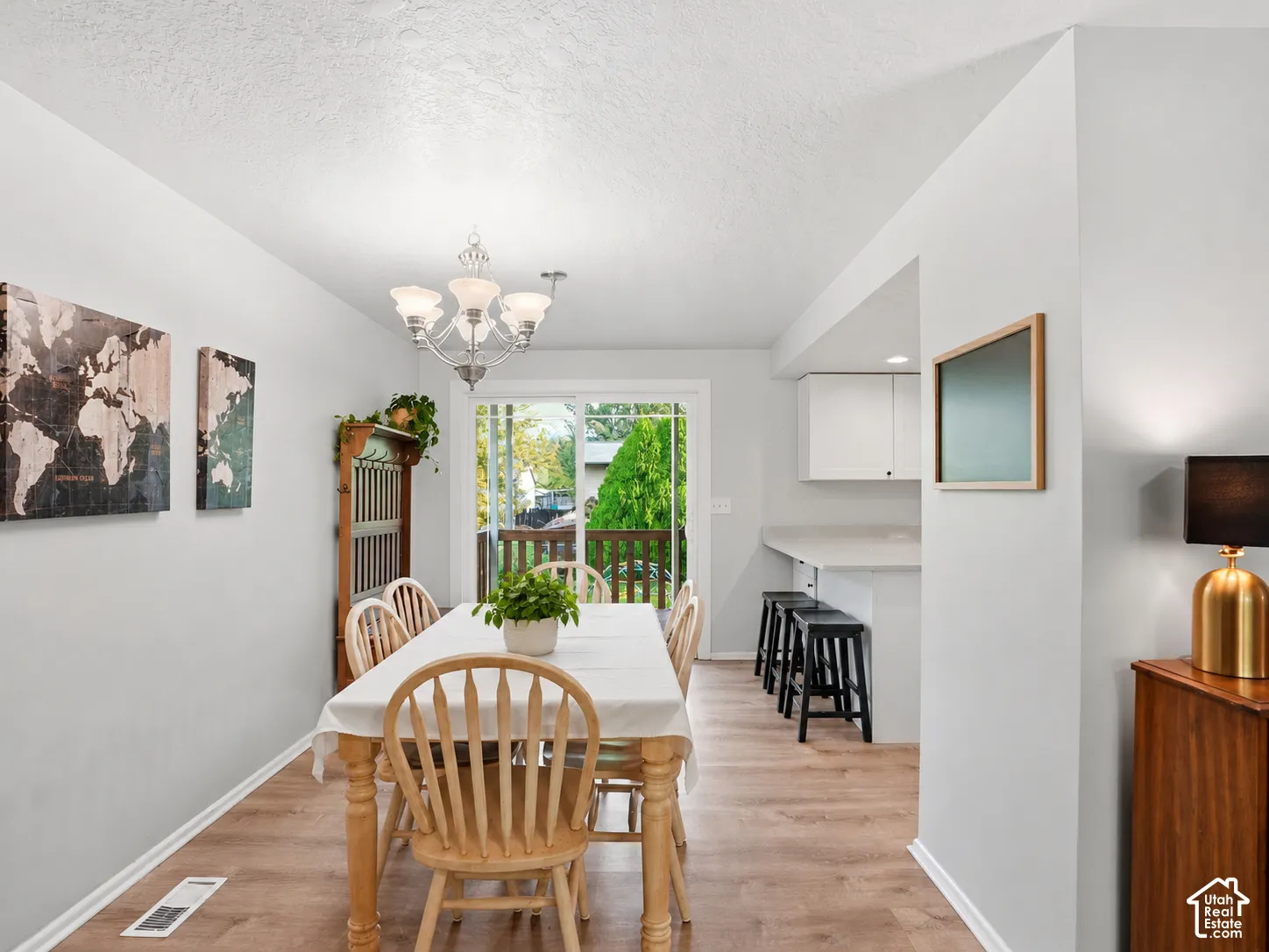 Dining space featuring wood-finish flooring, a decorative chandelier, and a sliding glass door providing access to an exterior deck