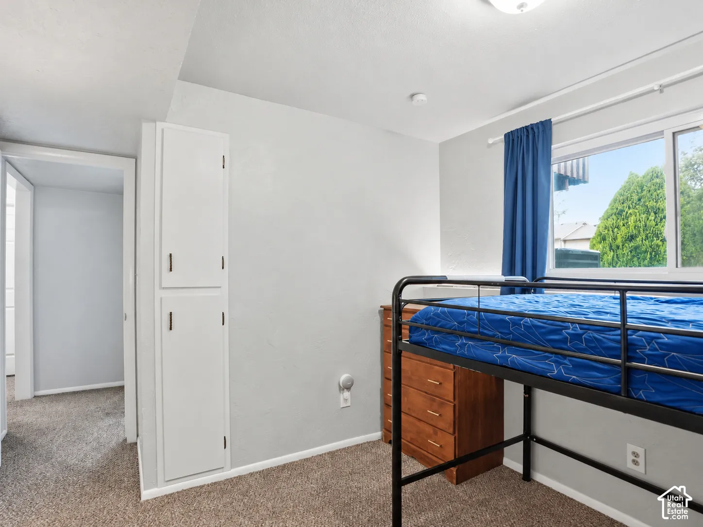 Built-in floor-to-ceiling cabinetry with white finish, horizontal sliding window, and neutral wall-to-wall carpeting