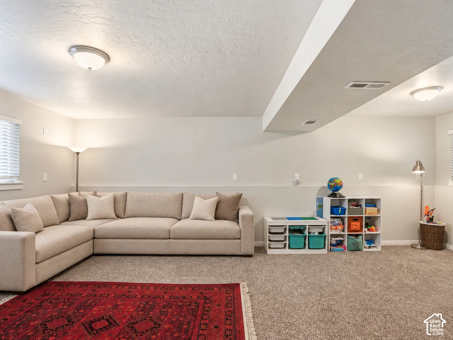 Neutral-toned interior space featuring textured wall-to-wall carpeting and two flush-mount ceiling light fixtures