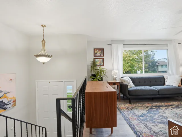 Open-concept interior featuring light-toned flooring, metal staircase railing, neutral wall color, and a decorative pendant light fixture