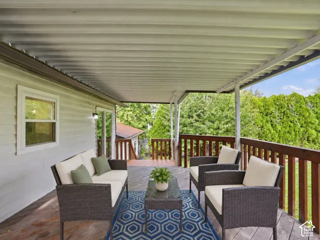 Covered deck featuring wood-plank flooring, a metal roof structure, and a wood railing