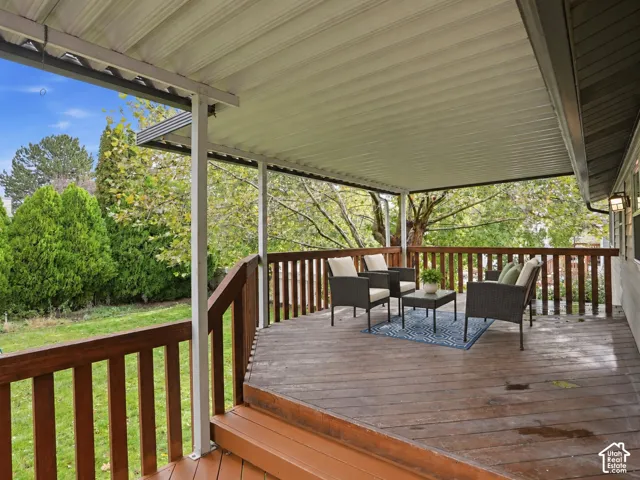 Covered deck featuring wood-finish decking, vertical wood railing, and overhead metal panel roofing