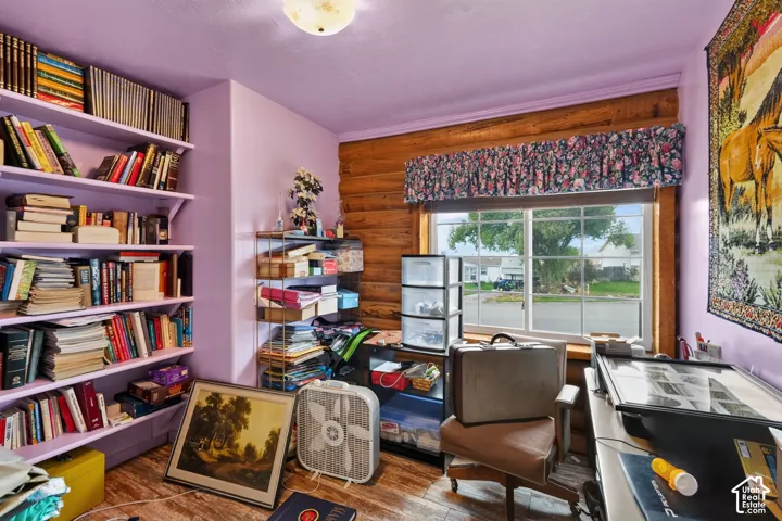 Interior room featuring horizontal log walls, built-in shelving, wood-finish flooring, and a multi-pane window