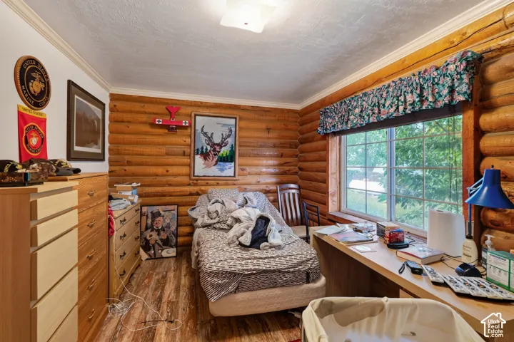 Log wall construction, wood-finish flooring, built-in wooden desk, and large window with exterior exposure