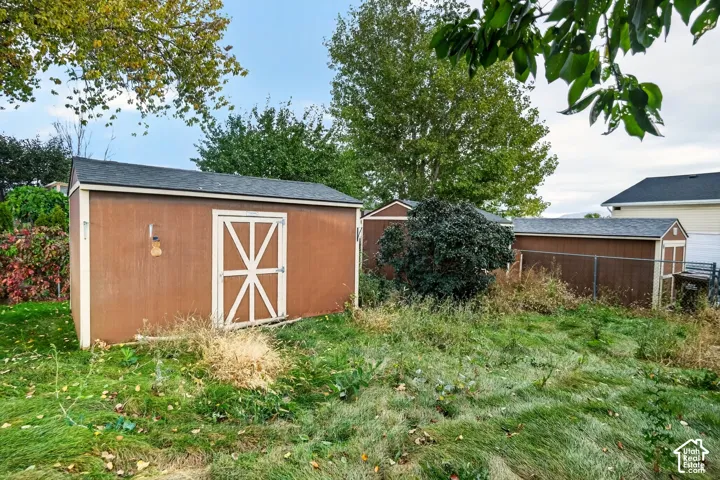 Exterior storage structures featuring wood-composite siding, shingled roofing, and double-door entry points