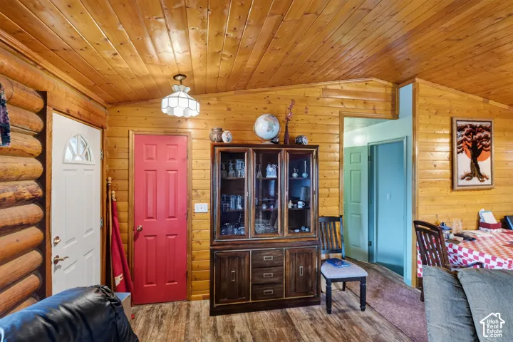 Interior featuring tongue-and-groove wood paneling, log wall construction, multi-tonal wood-finish flooring, and a glass-paneled entry door