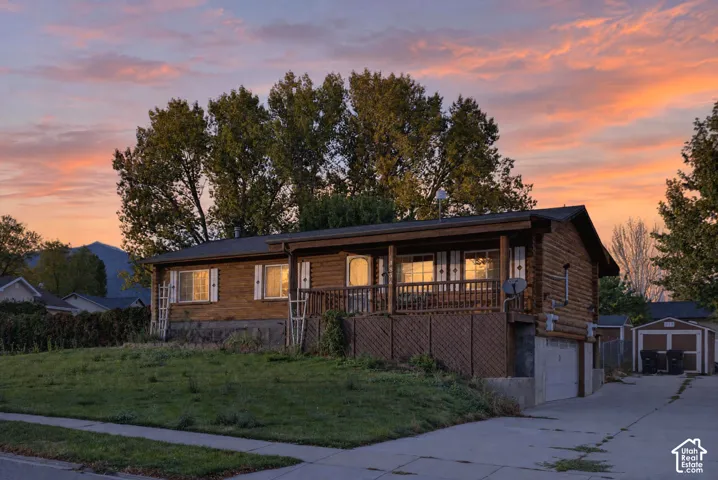 Log-style exterior featuring a covered front porch, mountain backdrop, and concrete driveway
