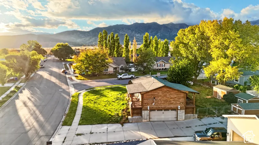 Aerial perspective featuring a wood-sided structure with a multi-level deck, attached garage, and mountain backdrop