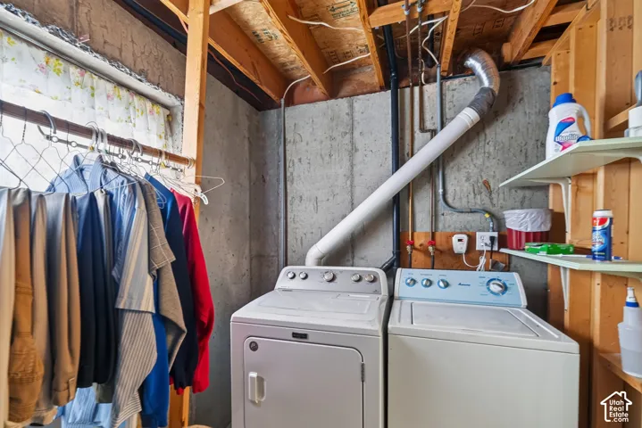 Utility area featuring exposed concrete walls, unfinished wood framing, built-in shelving, and washer and dryer hookups