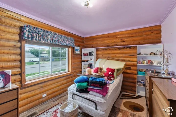 Interior room featuring exposed log walls, grid-pattern windows, wood-finish flooring, and dual built-in shelving units