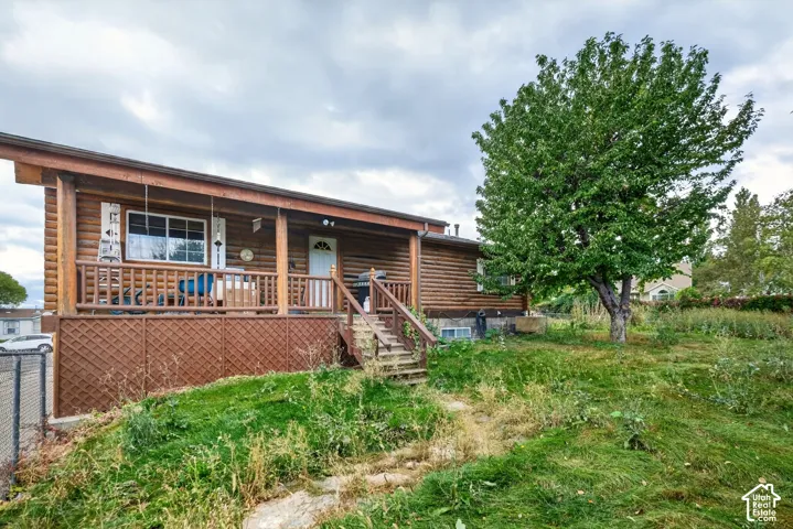 Log-style exterior with an elevated wooden porch, lattice skirting, and wooden stairs