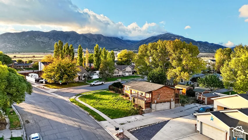 Aerial perspective featuring a residential setting with mountain range backdrop, mature trees, and landscaped lawns