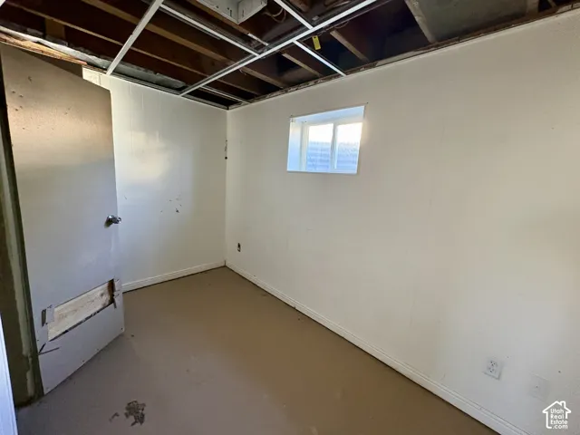 Interior space featuring smooth white walls, a single-pane sliding window, and an exposed ceiling structure with metal grid framing