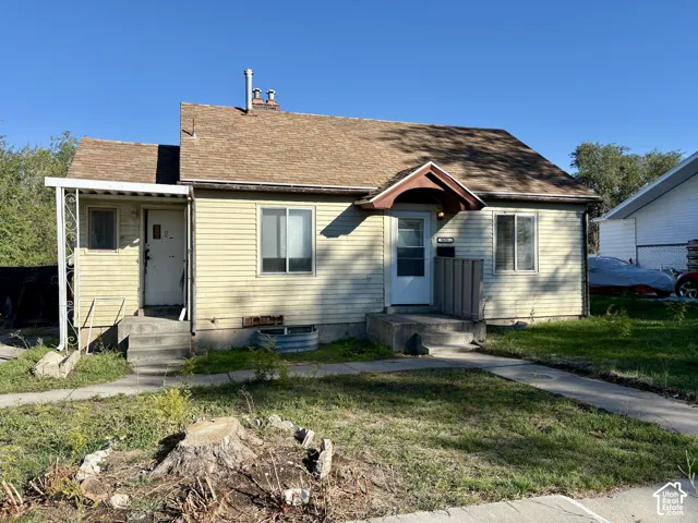 Single-story residence featuring light-colored horizontal siding, asphalt shingle roofing, a gabled front entry, and a covered side porch with decorative metal supports