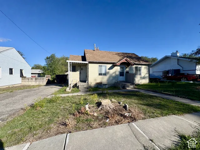 Single-story residence featuring light-colored horizontal siding, an asphalt shingle roof, a covered side entrance, and an attached concrete driveway
