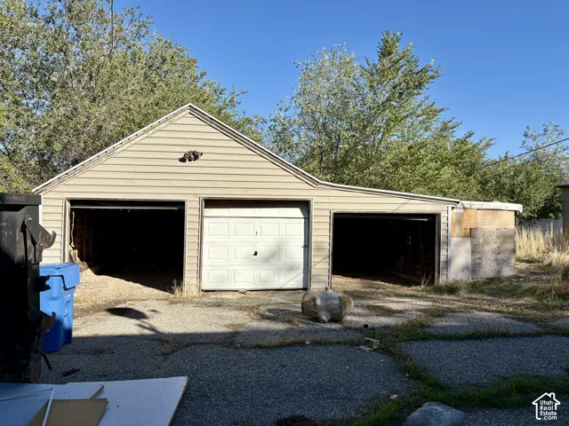 Detached garage featuring a combination of enclosed and open-bay parking with horizontal siding and an asphalt paved driveway