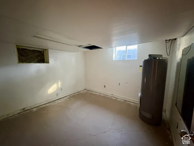 Utility room featuring a concrete floor, painted wall finishes, two glass-pane windows, and a tall water heater unit