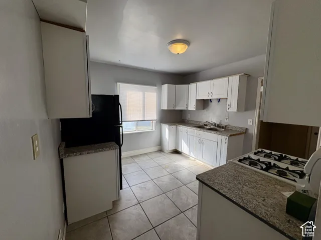 Kitchen featuring white cabinetry, stone-finish countertops, tiled flooring, and a flush-mount ceiling light