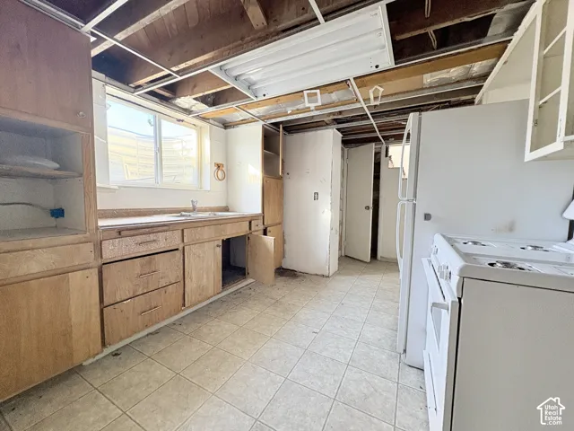Kitchen featuring wood-finish cabinetry, tile flooring, and integrated white appliances