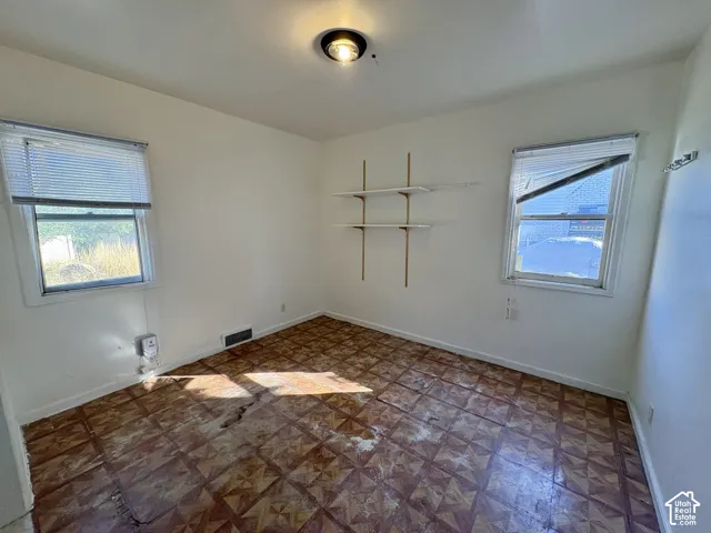 Room featuring patterned tile flooring, dual windows, and mounted wall shelving