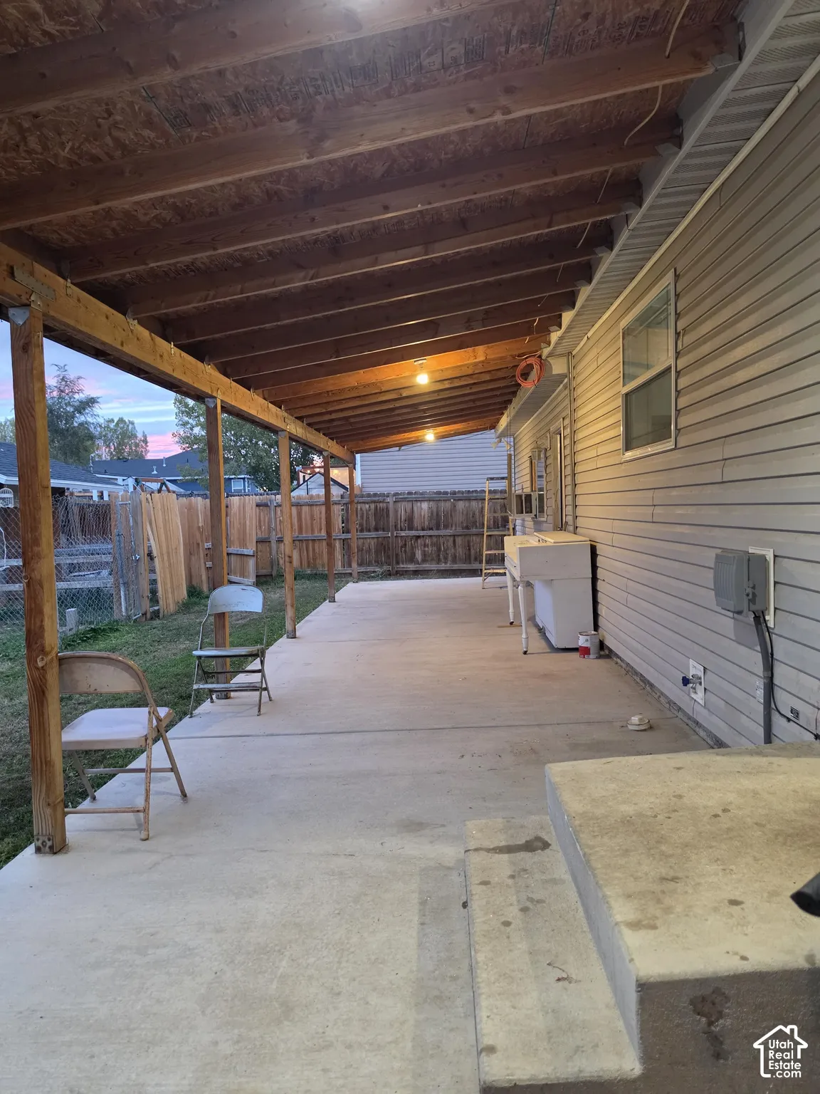 Covered patio with a concrete slab, exposed wood-beam ceiling, and vinyl siding