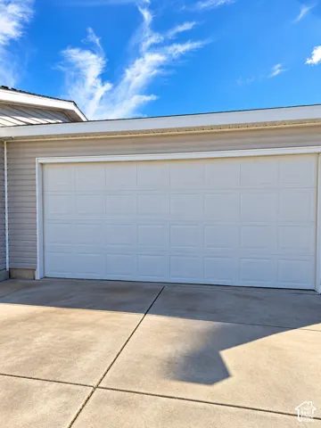 Attached garage featuring a panel-style door, light-toned siding, and concrete driveway