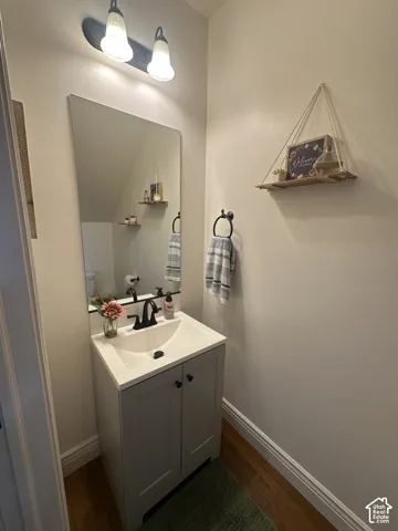 Gray cabinet vanity with a square sink, white countertop, matte black faucet, wall-mounted mirror, and two-light fixture