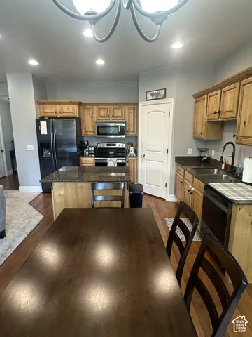 Kitchen featuring natural-finish wood cabinetry, dark stone countertops, an integrated island, recessed lighting, and wood-finish flooring