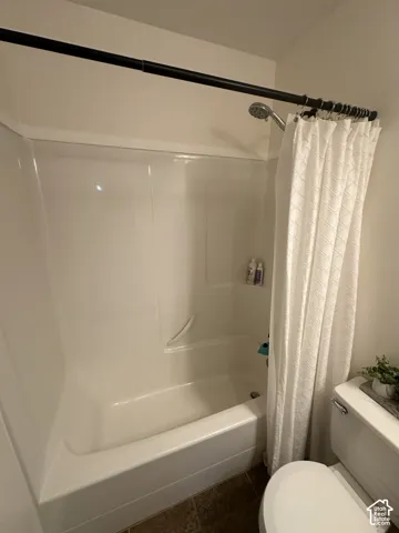 Bathtub and shower combination featuring a seamless white surround, integrated shelving, and a wall-mounted showerhead