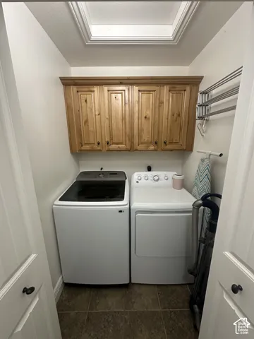 Laundry area featuring a skylight, natural wood finish cabinetry with crown molding, and tiled flooring