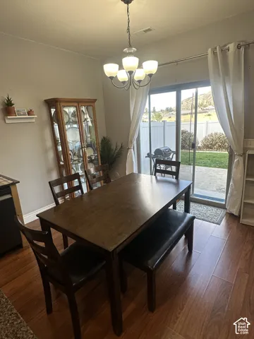 Wood-finish flooring, multi-light chandelier, sliding glass door, and backyard access featuring stone patio and mountain backdrop