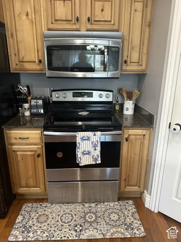 Kitchen featuring knotty wood cabinetry, stone countertops, and stainless steel appliances including a range and over-the-range microwave